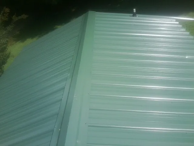 New green metal panels meeting at the ridge of a roof — Flat Roof Repair work by our crew in Jenkintown