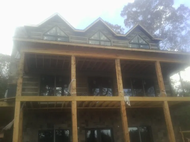 Dormers and porch framing on a large log home under construction — Roof Coating work by our crew in Jenkintown