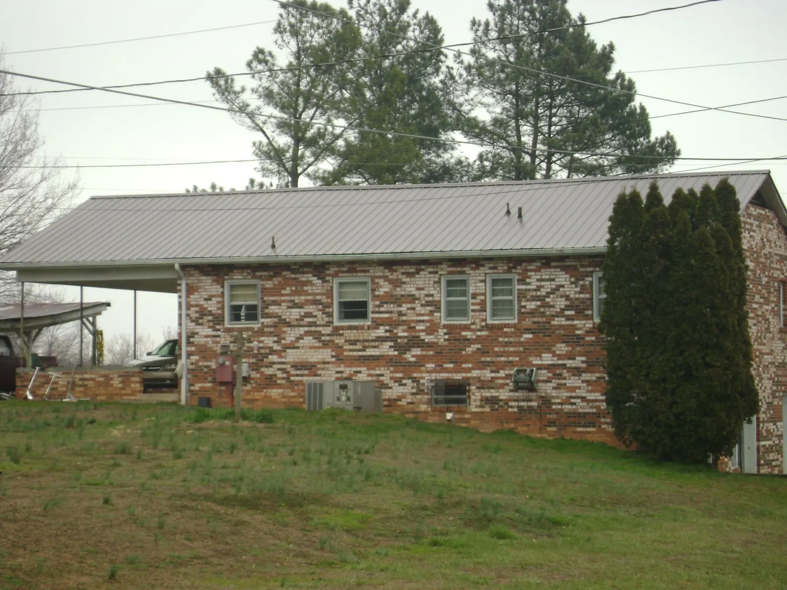 Gray metal roof on a brick split level home with a carport in Jenkintown