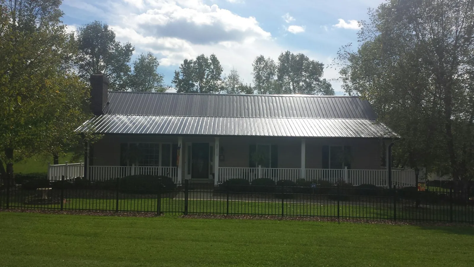 Gray metal roof on a brick ranch with a full width front porch — Gutter Guard Installation work by our crew in Jenkintown
