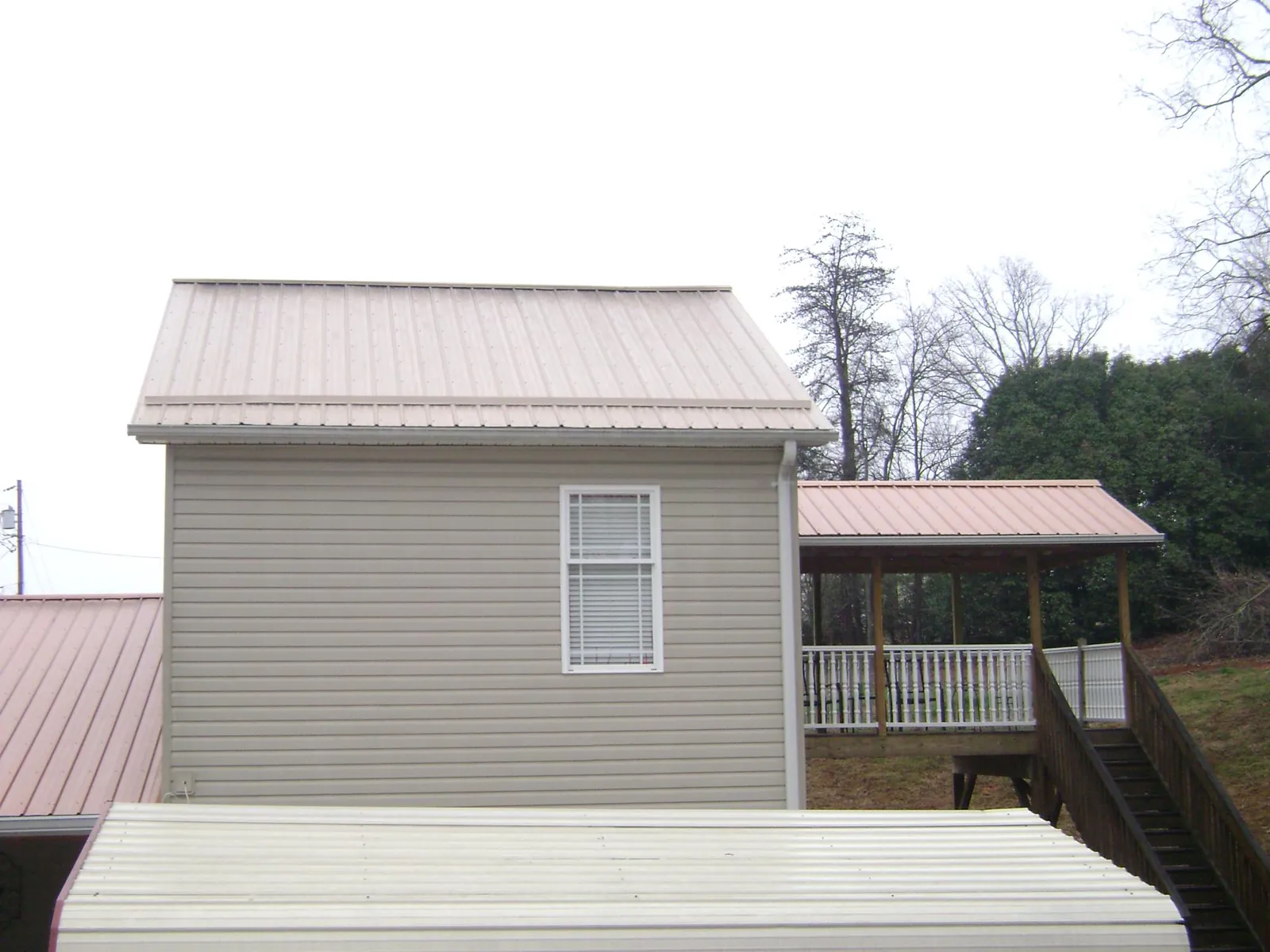 Tan metal roofs on a two story addition and attached porch, from a Roof Replacement job in Jenkintown