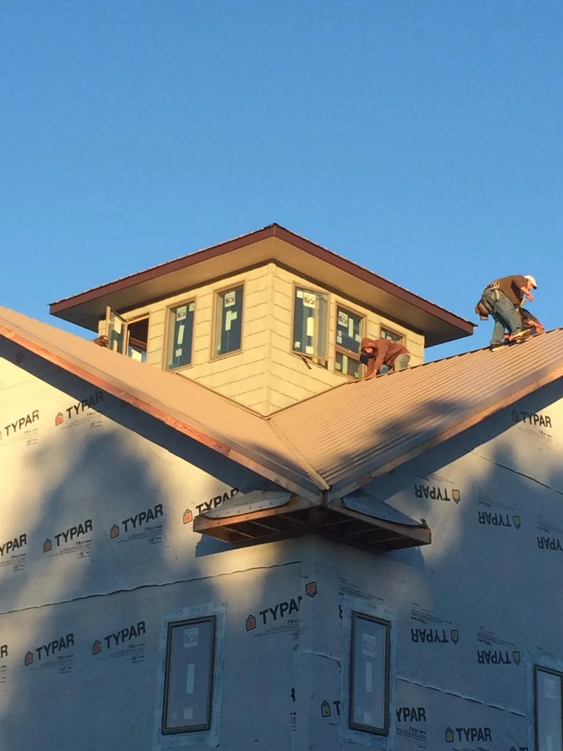 Roofers working around a rooftop cupola on a new metal roof at sunset — Roof Waterproofing in Jenkintown by Roofing Brothers